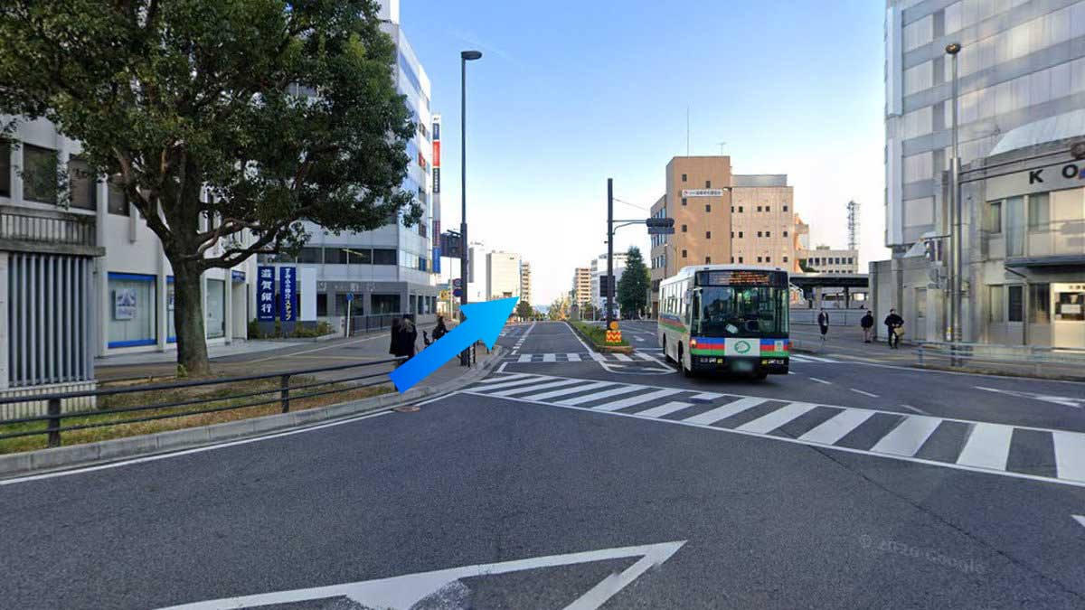 JR大津駅北口前の中央大通り。左手に滋賀銀行の青い縦看板、正面に琵琶湖へ向かう広い道路が続く。